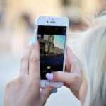 A person taking a photograph on their smartphone of a building.