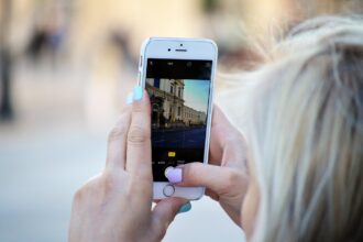 A person taking a photograph on their smartphone of a building.